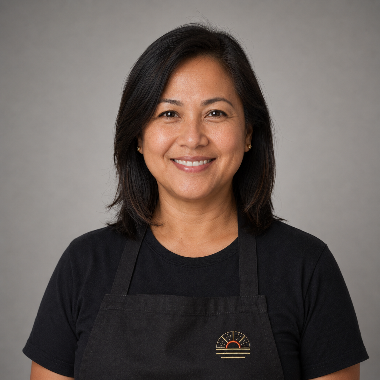 Mary Empeynado, Sales Development Representative, professional headshot wearing an apron with the sunburst logo
