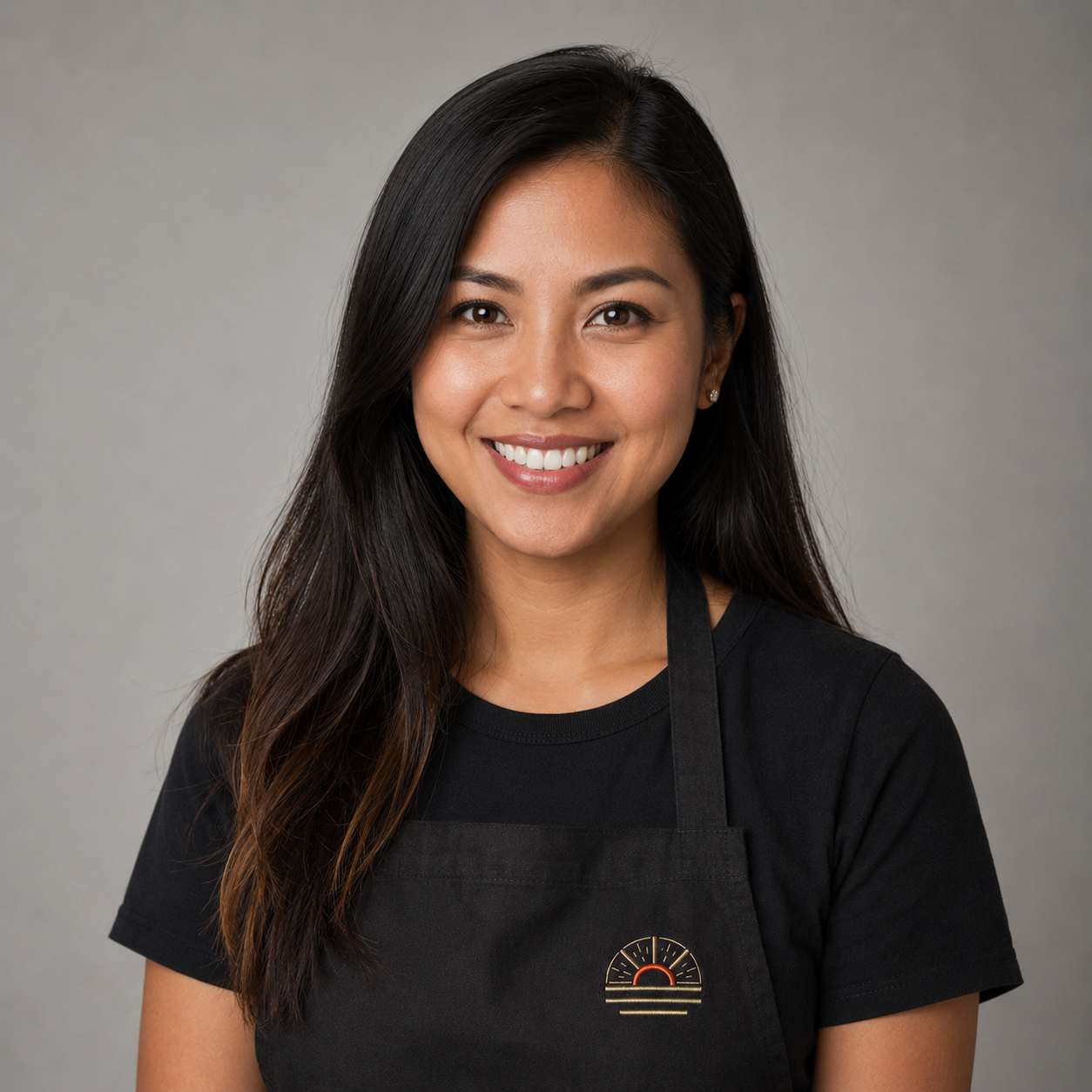 Reyjane Galarpe, Account Executive, professional headshot wearing an apron with the sunburst logo
